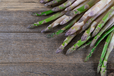 unch of fresh asparagus on a rustic wooden table for cooking in the kitchen.の写真素材