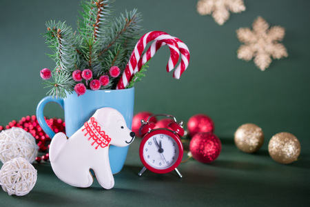 Christmas or new year card . Cup with fir trees, candy canes and red clock and cookies in the shape of a dog. On green bright background.の写真素材