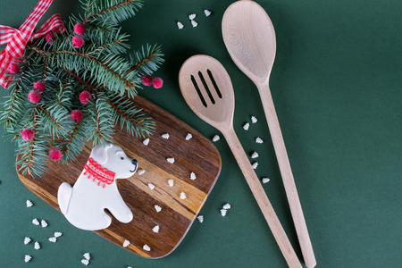 Gingerbread cookie in the shape of a dog. Fir trees with decoration and  kitchen tools on green background.の写真素材