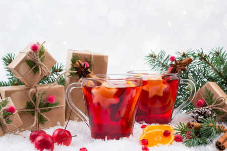 Traditional hot drink at Christmas time. Christmas mulled red wine with spices and fruits. On white snow backgroundの写真素材