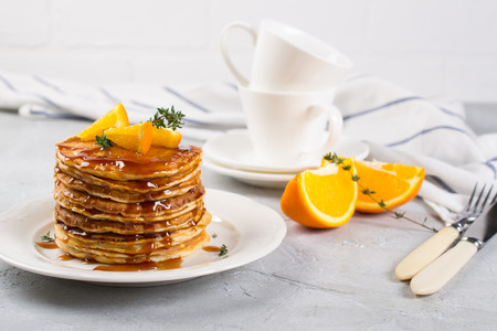 Table of breakfast . Pancakes with orange and sprinkled maple syrup, orange juice and coffeeの写真素材