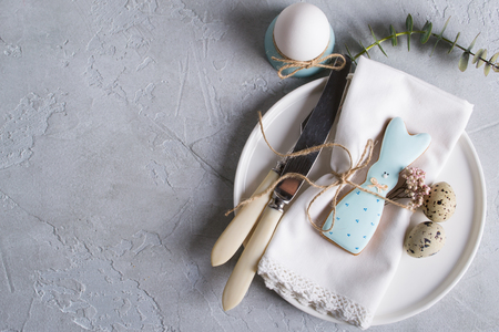 Homemade easter cookies in the shape of  a  funny  rabbit  on white plate. Easter  festive table setting. Holiday decorations.の写真素材