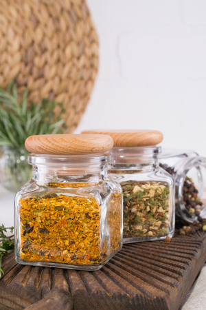Glass jars with dry spices for cooking on white tableの写真素材