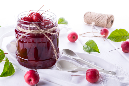 Glass jar of  small paradise apple jam with fresh fruits on white table. の写真素材