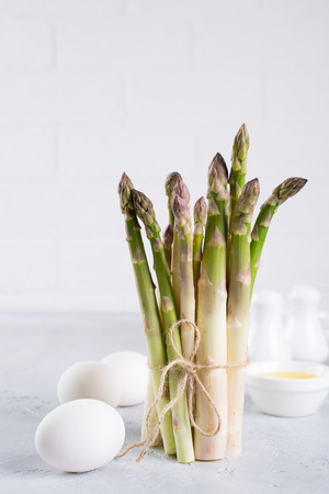 Bunch of raw fresh garden organic asparagus with eggs on a gray concrete background. Simple products for a healthy spring breakfast. Space for text Background for a recipe.の写真素材