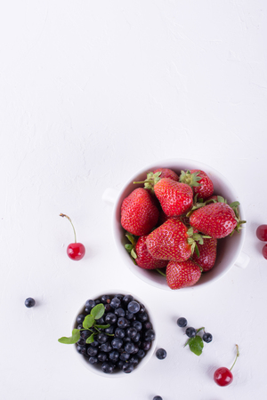 Fresh raw organic farm blueberryand strawberry in white bowl  on white background, copy space. Top viewの写真素材