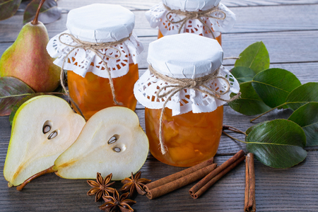 Pear jam and fresh pears cinnamon sticks, anise stars and green  leaves on the table.の写真素材