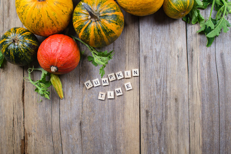 A frame of different pumpkins on an old wooden background, flat lay, top viewの写真素材