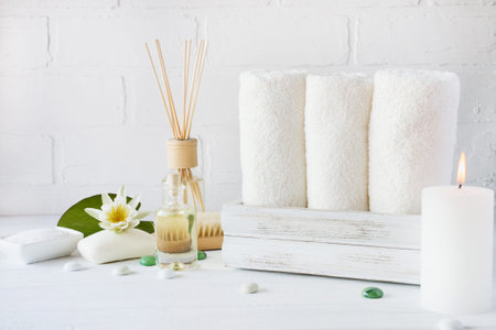 Spa setting and health care items, body oil, soap, candles, towel with lilac flower