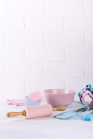 Baking background with kitchen tools: rolling pin, wooden spoons, whisk, sieve, bakeware and shape cookie cutter on white wooden background.の写真素材