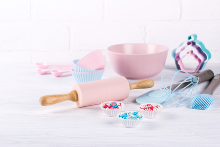 Baking background with kitchen tools: rolling pin, wooden spoons, whisk, sieve, bakeware and shape cookie cutter on white wooden background.の写真素材
