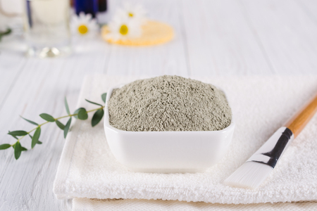 Preparing cosmetic mud mask with various skincare products. Dry clay powder in bowl. Natural cosmetics for home or salon spa treatment. On white background.の写真素材