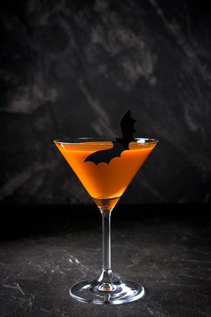 Orange pumpkin  martini Halloween drink for party over black background with copy spaceの写真素材