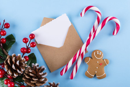 Envelope, paper card and decoration on blue table top view. Christmas mockup for greeting. Flat lay....