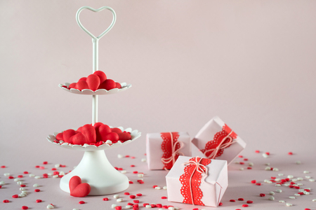 Valentine's day concept. White two tier serving tray full of multicolor sweet sprinkles sugar candy hearts and packing Valentine's  Day giftsの写真素材