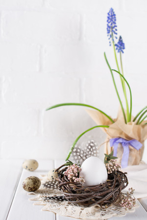Easter spring decorative composition  with white chicken egg in a nest with flowers. Holiday decorations. Easter  festive table settingの写真素材