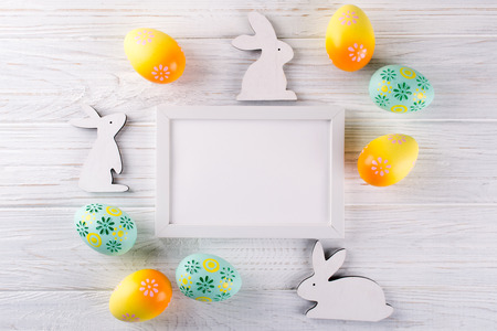 Easter mock up with photo frame.  Colorful easter eggs, and decorative wooden bunny. Celebration, holiday concept. Flat lay, top view, copy spaceの写真素材