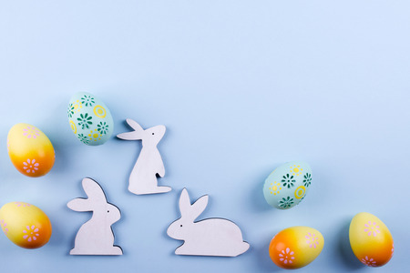 Easter holiday background with eggs. Top view of colorful painted chicken eggs and decorative wooden bunny. Flat lay, copy spaceの写真素材