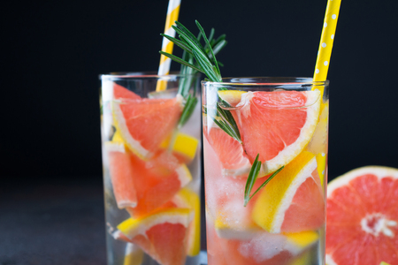Grapefruit lemonade. Two glasses of refreshing drink, water with  grapefruit, rosemary branches and ice. Recipe concept, cocktailの写真素材