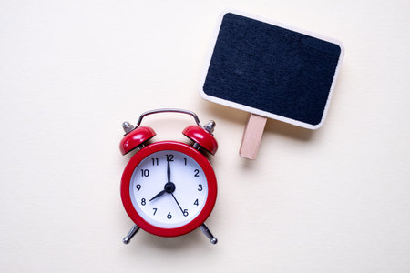 Blank vintage small chalkboard for text on purple background and a red alarm clock. . Minimal...