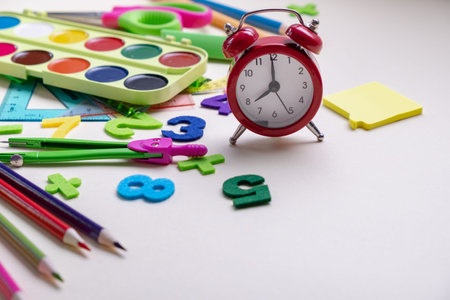 Concept back to school. Alarm clock and School supplies.