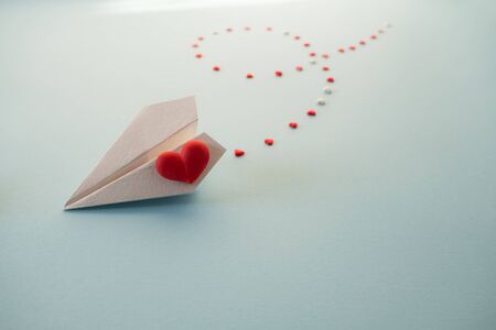 Valentine's Day background. Single white paper plane with red heart on a pastel blue background.の写真素材