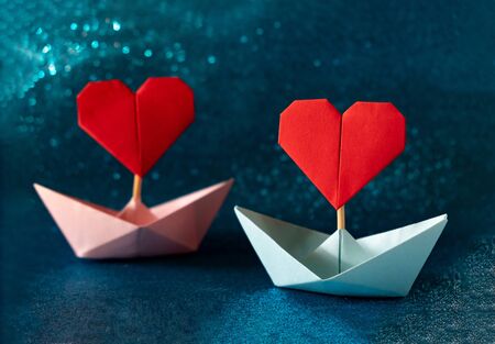Pink and blue paper boat on glitter blue background. Romantic, Valentines day concept with space for text.の写真素材