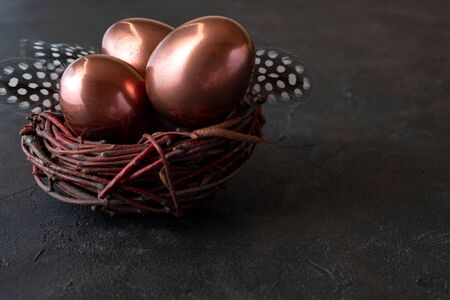 Easter composition with eggs in a nest  and feather on dark background. Easter greeting cardの写真素材