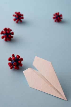 Concept of fly danger. Paper plane and models of covid-19 virus on blue backgroundの写真素材