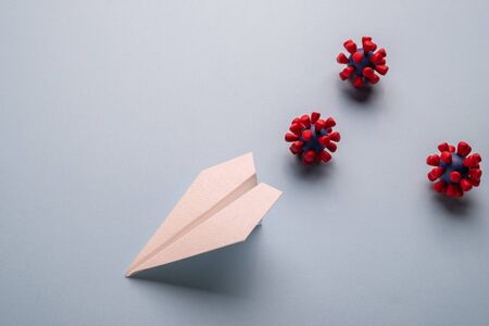 Concept of fly danger. Paper plane and models of covid-19 virus on blue backgroundの写真素材