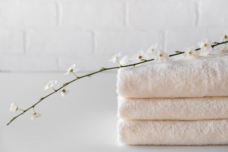 Stack of three white fluffy bath towels with  branch. Spa composition  Copy spaceの写真素材