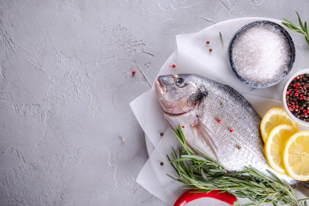 Delicious raw dorado or sea bream fish with lemon spices, fresh rosemary on marble board view from...