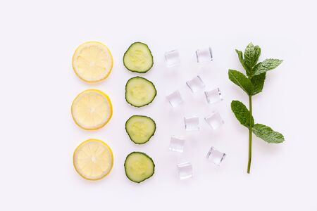 Creative summer drink composition. With lemon slices, mint leaves , cucumber and ice cubes. Minimal flat lay lemonade drink concept. On white backgroundの写真素材