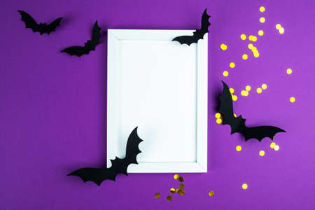 Halloween composition mock up. White photo frame, flying black paper bats on purple background. Flat lay, top view, copy spaceの写真素材