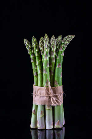 Asparagus. Bunch of fresh green asparagus tied on black background.の写真素材