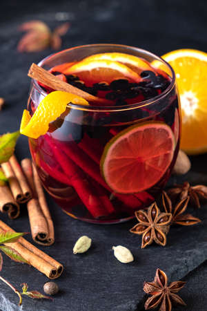 Delicious red wine with spices. Mulled wine and ingredients on dark tableの写真素材