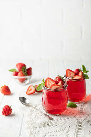 Sweet dessert jelly pudding with strawberries in glass jar on white backgroundの写真素材