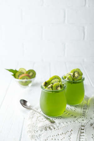 Sweet dessert jelly pudding with kiwi in glass jar on white backgroundの写真素材