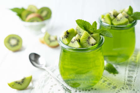 Sweet dessert jelly pudding with kiwi in glass jar on white backgroundの写真素材