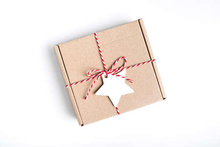 Packing Christmas gifts. Eco craft holidays gift box tied with red and white string, decorations on white Present decorated with natural parts Top view with copy spaceの写真素材