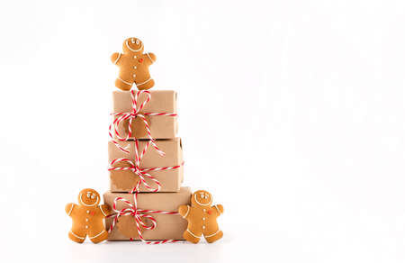 Stack of Christmas gifts boxes in craft paper with crunchy gingerbread men cookies. Merry Christmas concept on white backgroundの写真素材