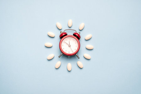 Time to take pills. Clock created from white pills on blue background. Right time for using medicinesの写真素材