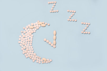 Medical supplement in the evening. Concept Insomnia, sleep problems. Pills in shape of the moon and alarm clock on blue backgroundの写真素材