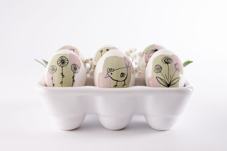 Modern creative trendy hand painted easter egg in a ceramic stand on white background. Homemade...