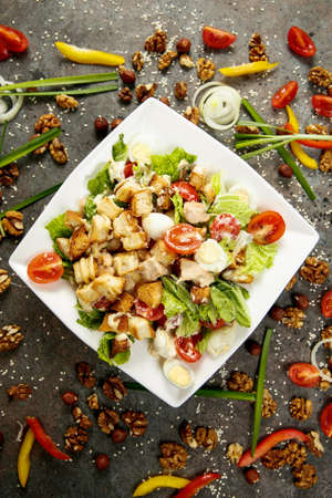 Greek salad on a white square plate on gray wooden backgroundの写真素材