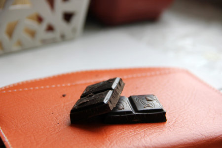 The dark chocolate pieces on orange backgroundの写真素材