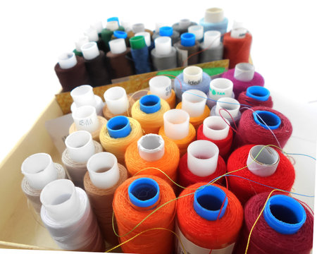 Multicolored spools of thread on white background