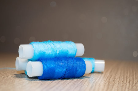 Light and bright blue spools of thread on the table on a blurry background
