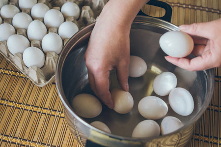 Hands put white fresh chicken eggs in a cooking pot for Easter