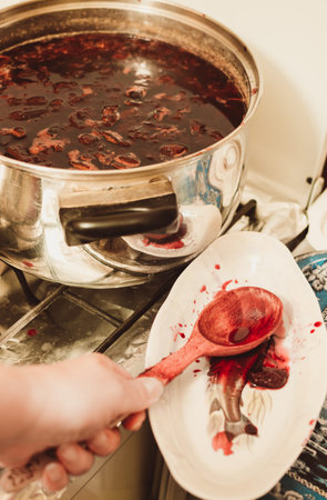 A large pot of red hot plum jam and dishes on the gas stoveの写真素材